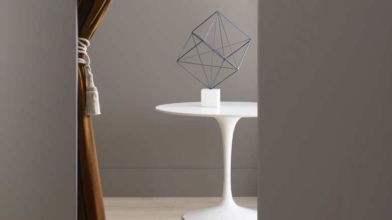 A table and curtain behind a wall painted a deep taupe color