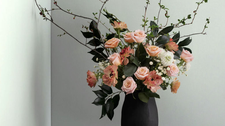 A vase full of flowers sitting in front of a light green wall