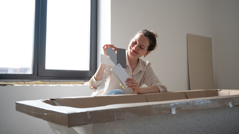 A woman looking at color samples in a bathroom