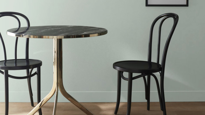 Two chairs and a table in front of a sage green wall