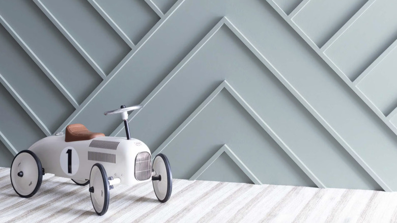A white toy car in front of a blue-gray textured wall