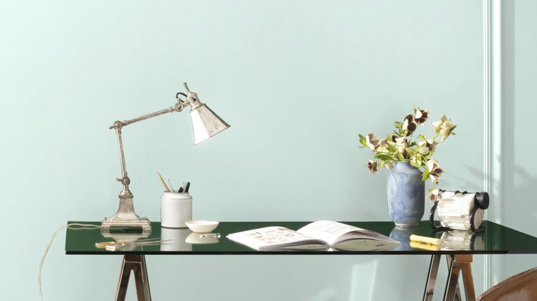 A wall behind a desk painted a mint green color