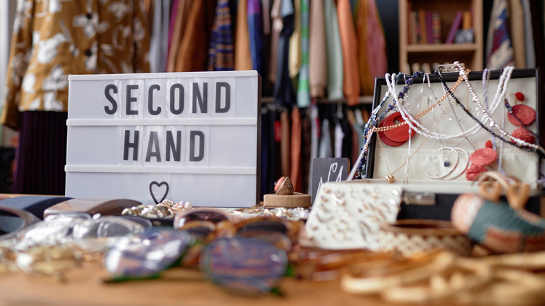 A second hand sign and assorted knick-knacks, jewelry, and other objects in thrift store