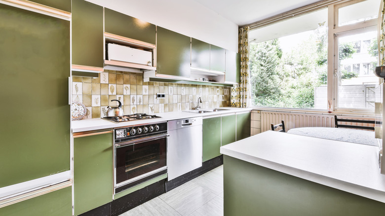 Retro kitchen with green 60s-style cabinets and checkered backsplash