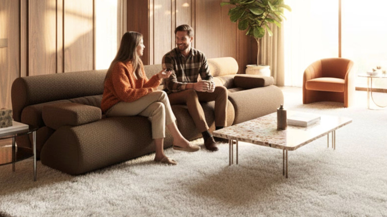 Man and woman sitting on low-profile couch in a 70s inspired living room.