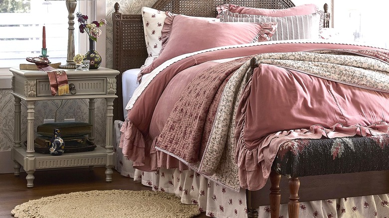 Vintage-style bed in pink and off-white linens with a bed-skirt in a floral pattern.