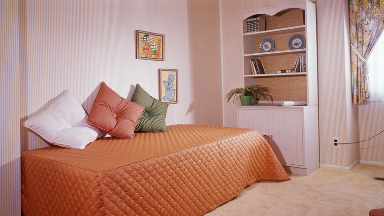 1980s Single Daybed Orange Quilted Cover three Throw Pillows Bookcase Wall To Wall Carpeting Bedroom Studio Apartment