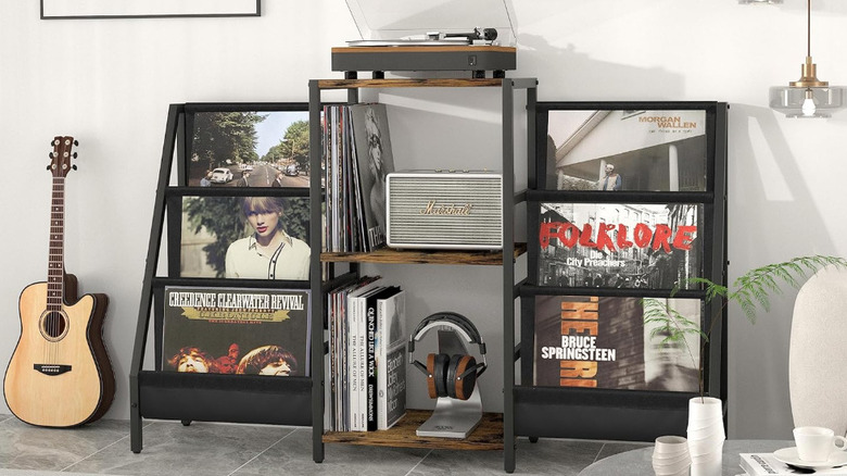 A guitar next to the Tewinko record stand with vinyl albums on display.