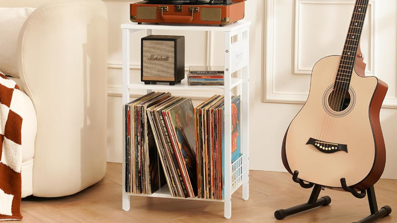 The white Yoobure record player stand next to a guitar.