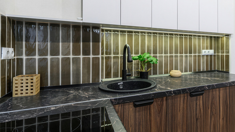 A kitchen with a dark olive green backsplash