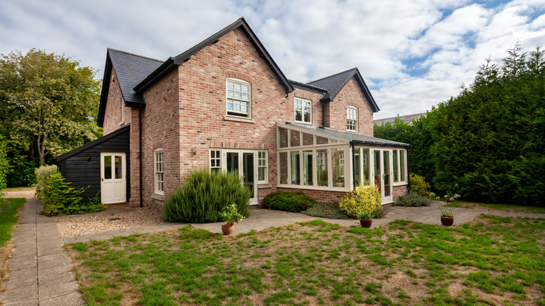 A brick house with a patchy front lawn
