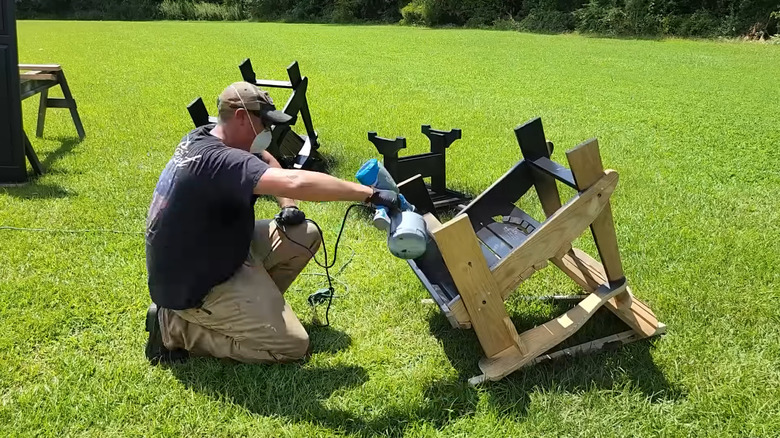 a man uses a paint sprayer to seal wood furniture