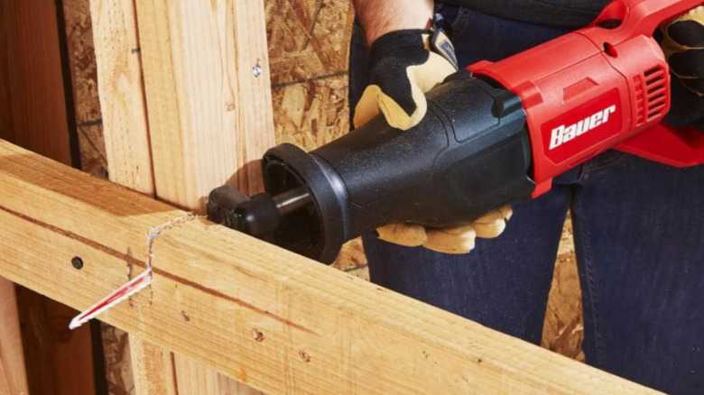 a person uses a reciprocating saw to cut a 2x4