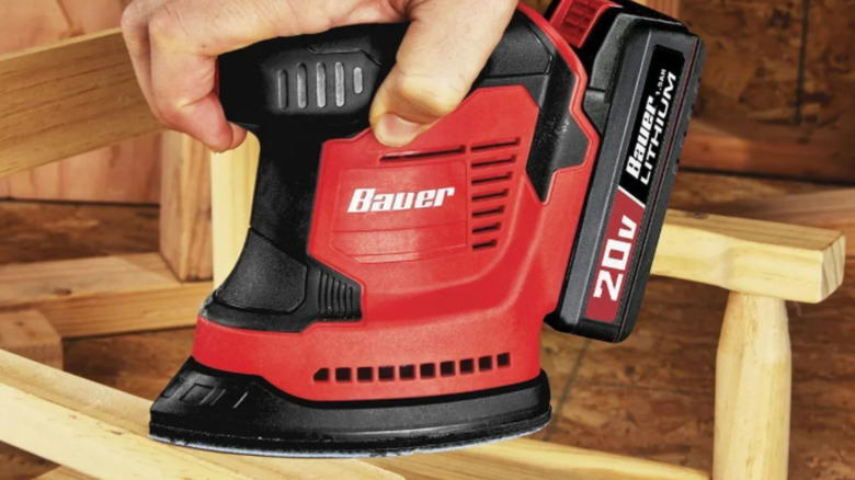 a person uses a palm sander on a piece of wood