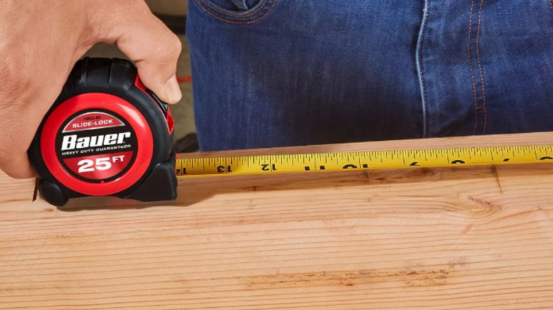 a person holds a tape measure extended out on a board