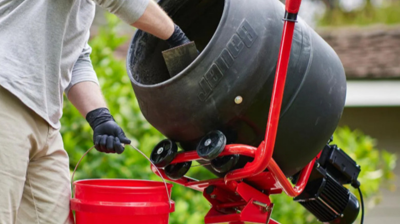 a person uses an electric cement mixer