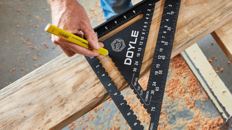 a person makes markings on a board with a rafter square