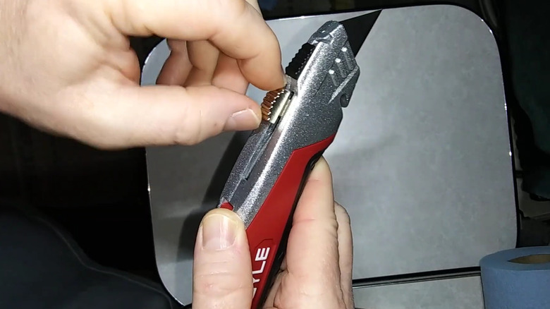 a person holds a retractable utility knife