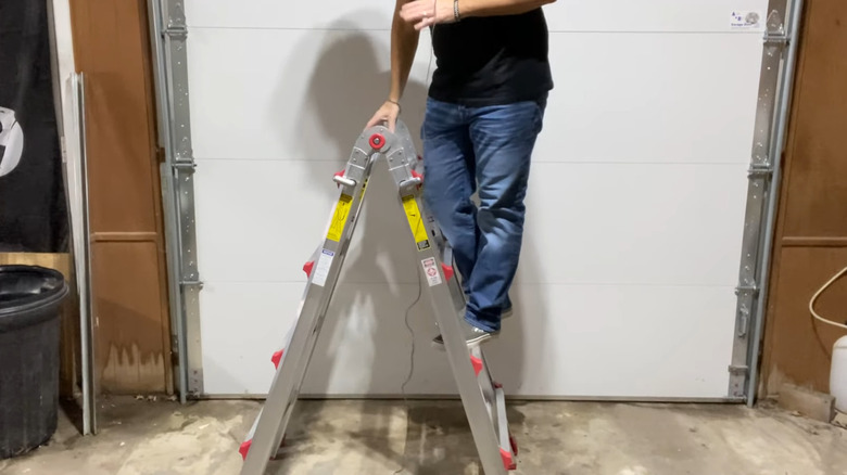 a man stands on a multitask ladder in the short position