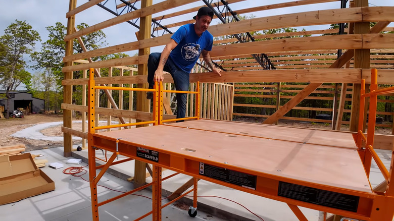 a man climbs onto scaffolding at a job site