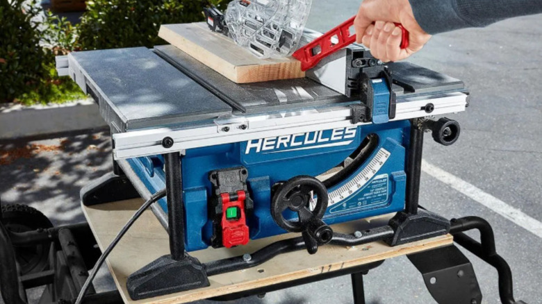 A person runs a board through a hercules table saw