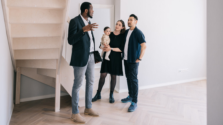 A real estate agent shows a young family a finished basement