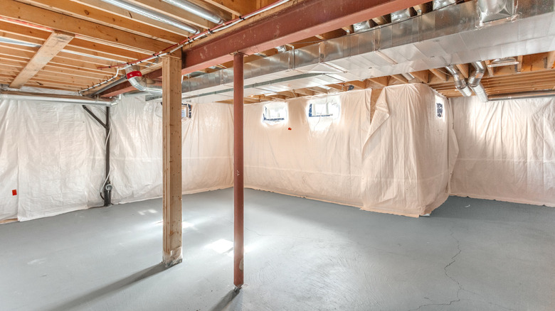 A spacious unfinished basement has exposed beams and pipes