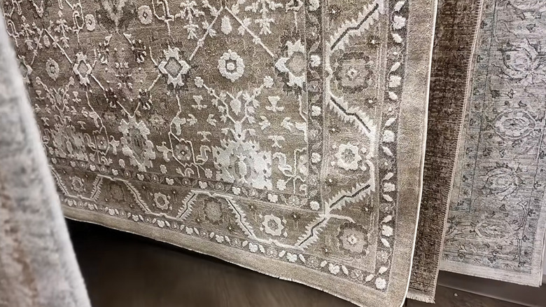 Several neutral rugs hanging on display in HomeGoods