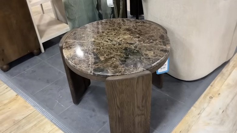 A brown stone side table sits on the floor of HomeGoods