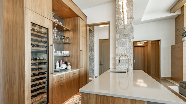 A galley kitchen with natural stone and wood elements, and a wine fridge