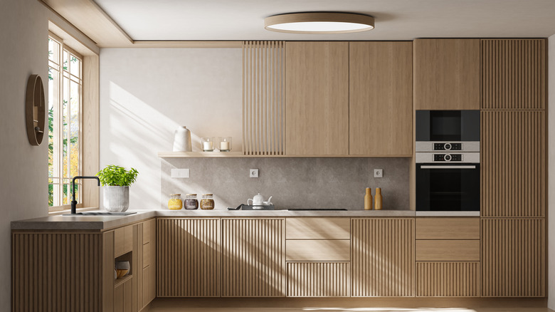 A kitchen with light wooden cabinets and only on open shelf