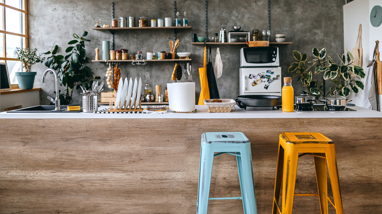 A kitchen with a darker textured wall, and pops of yellow and blue throughout