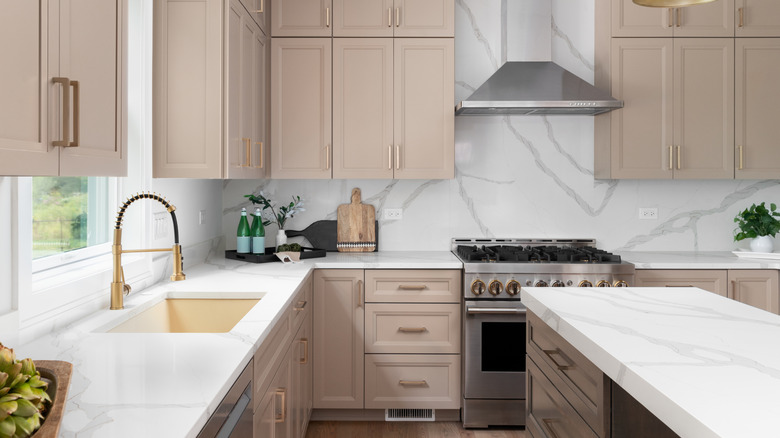 A white kitchen with light brown cabinets and a mix of finishes