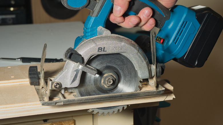 A man cutting a piece of plywood with a circular saw