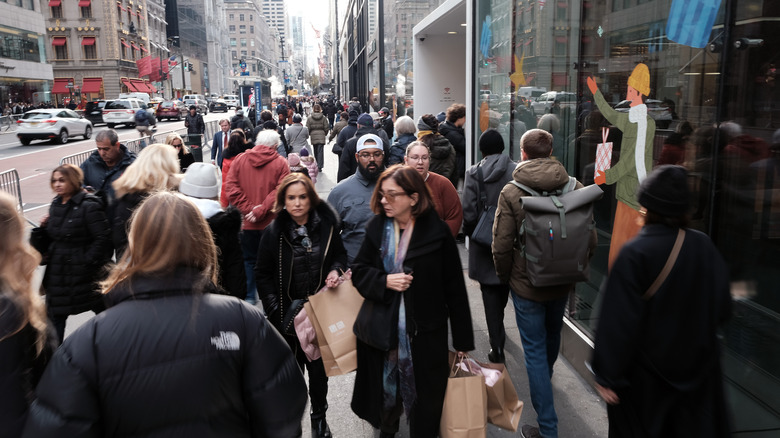 Pedestrians walk along crowded sidewalk