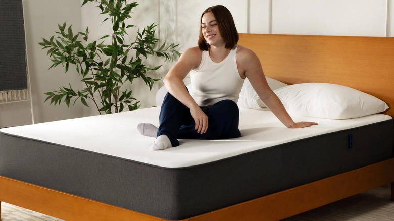 A woman sitting on a Casper Cooling Memory Foam Mattress in a bedroom