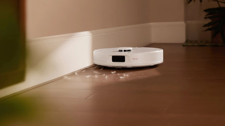 A white vacuum and mop robot cleaning a wooden floor