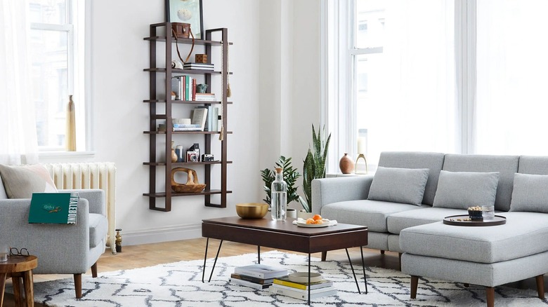 A Burrow Index Wall Shelf on a wall in a living room full of books and trinkets.