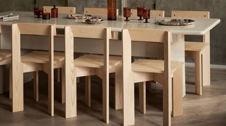A set of Ferm Living Ark Dining Chairs around a large dining table with modern tableware on it.