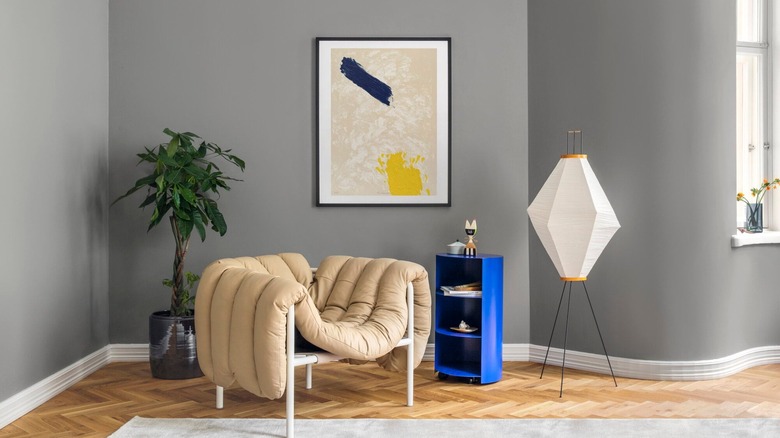 A Puffy lounge chair by Hem in a living room next to a bright blue shelf, green plant, and some simple art.