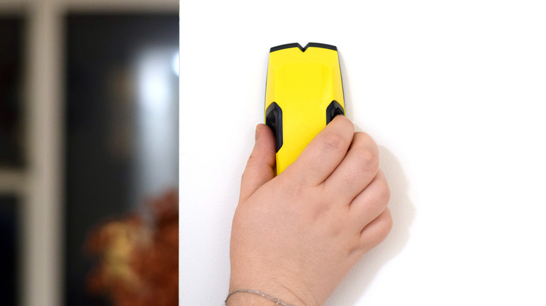 person using yellow stud finder