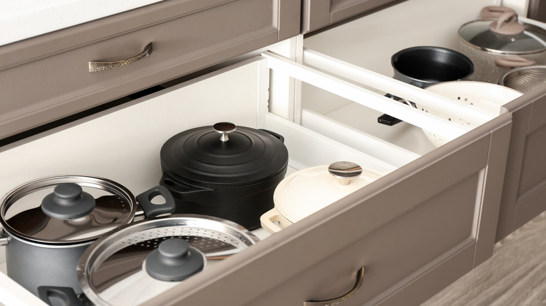 Cookware stored in a single layer in deep drawers with enough space for lids