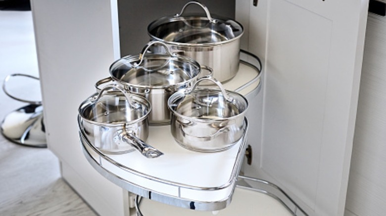 White and chrome blind corner shelves with an organizer holding pots