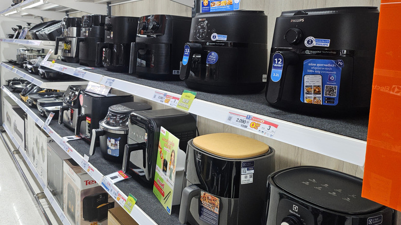 Air fryers are displayed on two store shelves
