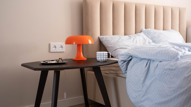 Orange mushroom lamp on a space-age mid-century modern style bedside table in a modern bedroom.