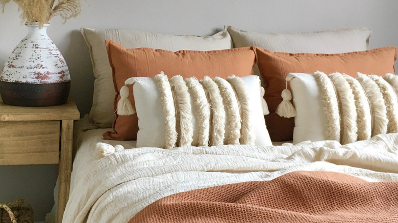 Closeup of bed with beige and terracotta bedding