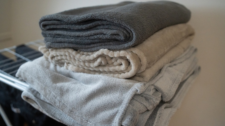 Stack of neutral-colored blankets folded on top of a wire shelf