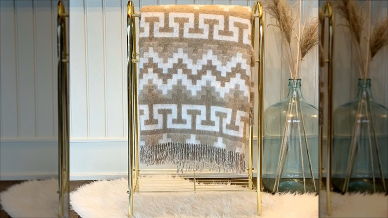 Brass blanket holder with a large throw hanging on it