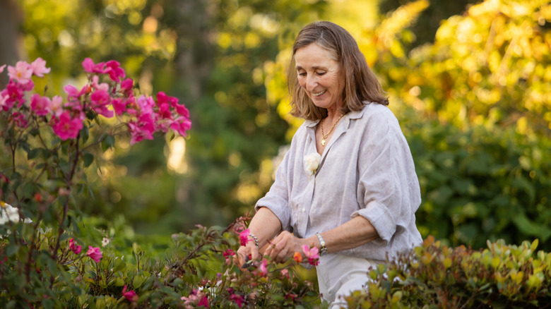 A smiling woman pruning flowering shrubs in the garden