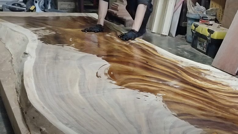 Man overlaying finish on live edge acacia table